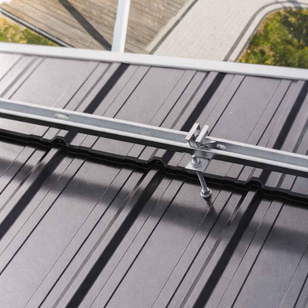 Кріплення для сонячних панелей: монтажний оцинкований профіль і кронштейн на металевій покрівлі, вузол фіксації рейки.