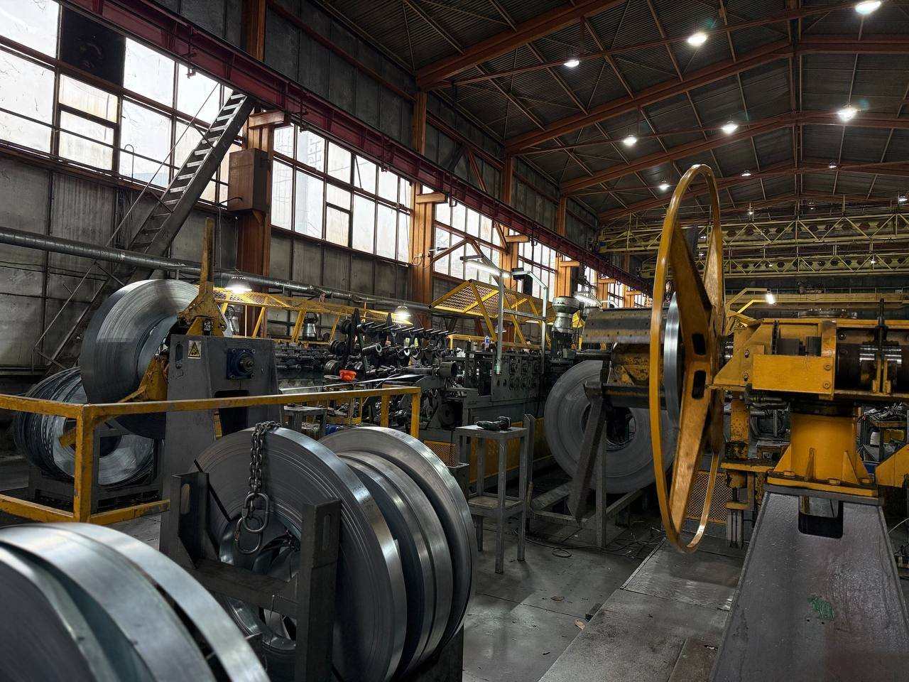 Производственная линия Loveks-K: рулоны оцинкованной стали и оборудование для переработки металлопроката в цеху.